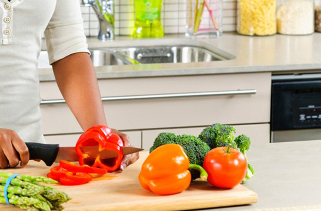 mulher cortando legumes na cozinha utilizando dicas de culinária